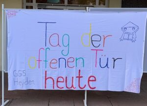 Banner mit dem Logo der Schule und dem Text "Tag der offenen Tür heute" in bunten Lettern